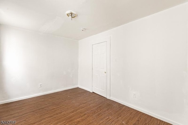 unfurnished room featuring baseboards and dark wood-style flooring