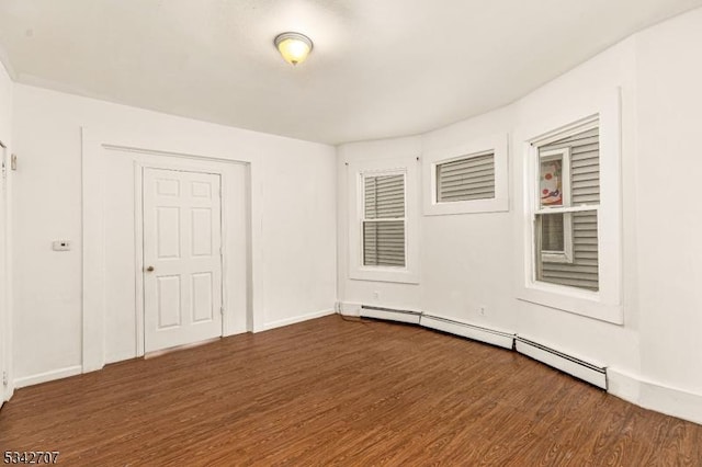 spare room with dark wood-style floors, baseboards, and a baseboard radiator