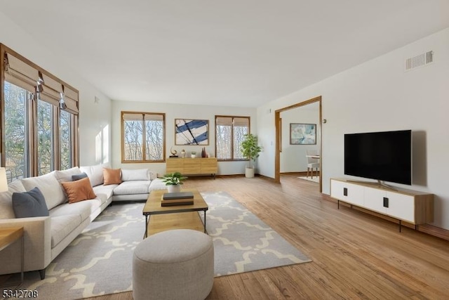 living room featuring visible vents, baseboards, and wood finished floors