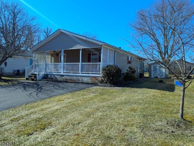 view of front of property with covered porch, an outdoor structure, a front lawn, and a shed