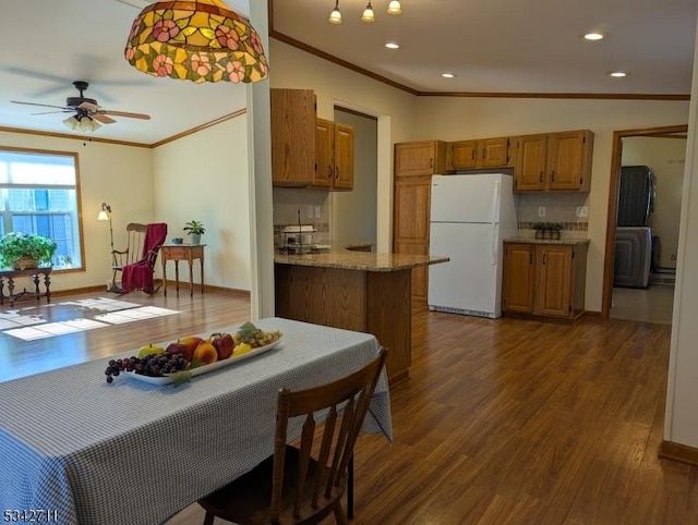 kitchen with dark wood-type flooring, brown cabinetry, freestanding refrigerator, and crown molding