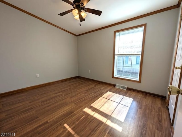 spare room with ceiling fan, wood finished floors, visible vents, baseboards, and crown molding