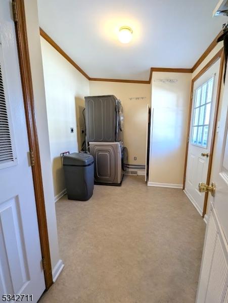 clothes washing area featuring ornamental molding, laundry area, stacked washer and clothes dryer, and baseboards