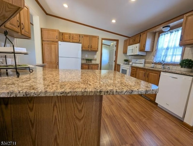 kitchen with ornamental molding, vaulted ceiling, a sink, white appliances, and a peninsula