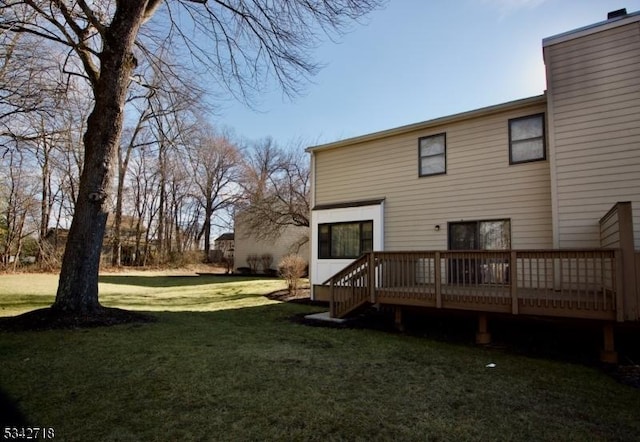 back of property with a lawn, a chimney, and a deck