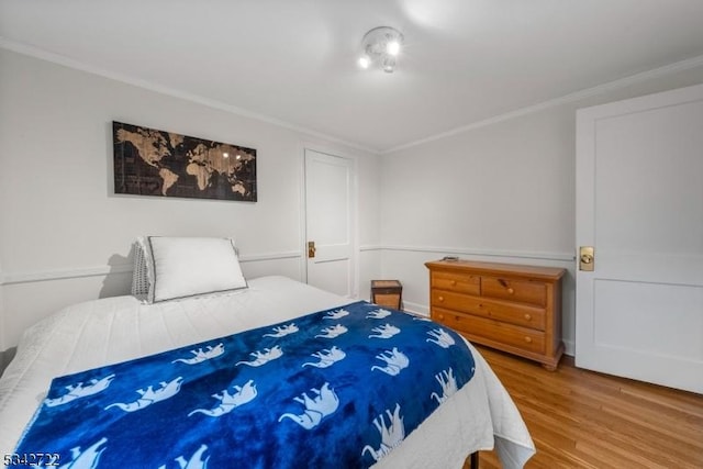 bedroom with wood finished floors and crown molding