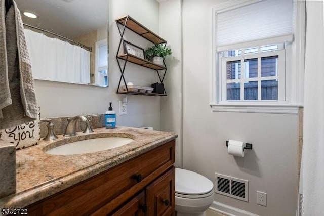 bathroom with toilet, vanity, and visible vents