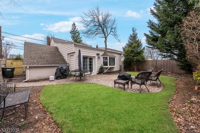 back of house with a fenced backyard, a lawn, a patio, and roof with shingles