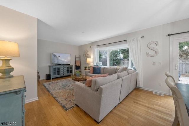 living area with a healthy amount of sunlight, light wood finished floors, baseboards, and visible vents