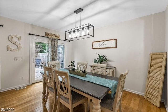 dining space featuring light wood-type flooring, visible vents, and baseboards