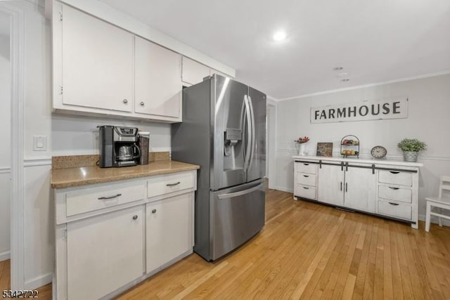 kitchen featuring light countertops, white cabinets, stainless steel fridge, and light wood-style flooring