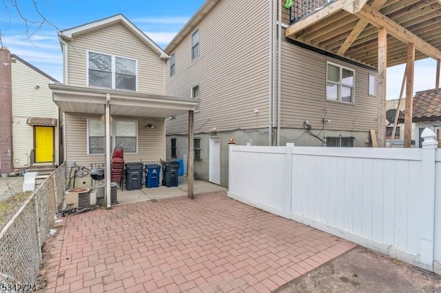 rear view of property with entry steps, a patio, central AC, and fence private yard