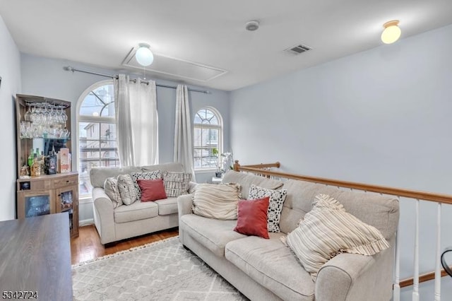 living room featuring attic access, visible vents, and wood finished floors