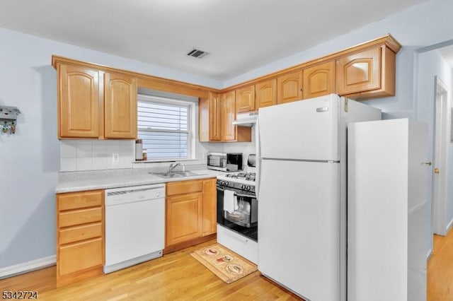 kitchen featuring under cabinet range hood, white appliances, a sink, visible vents, and light wood-type flooring