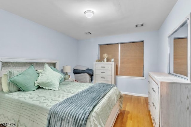 bedroom with light wood-style floors, visible vents, and baseboards