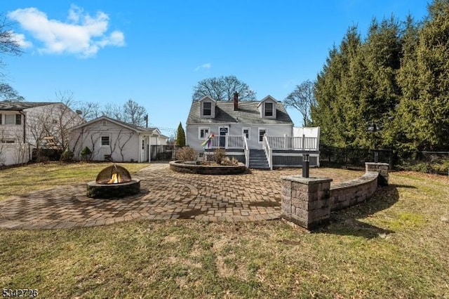 back of property featuring a fire pit, fence, a lawn, a wooden deck, and a patio area