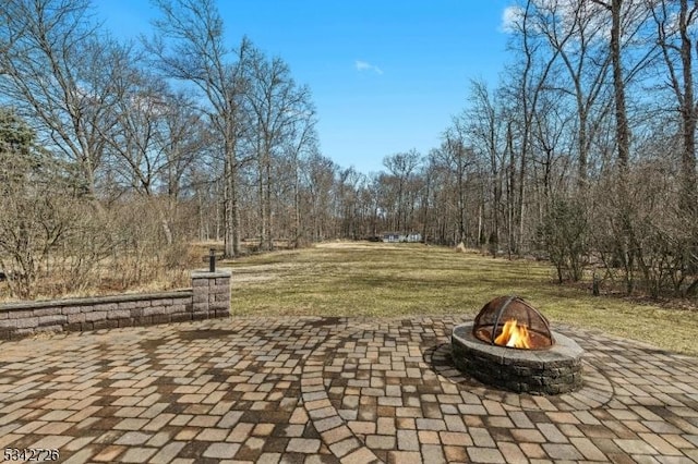 view of patio / terrace with an outdoor fire pit and a view of trees