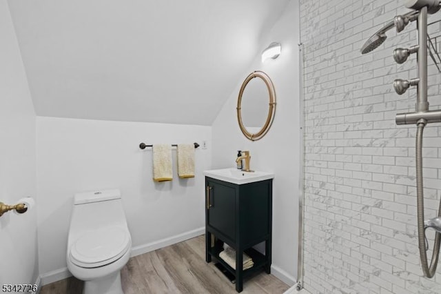 full bath featuring tiled shower, lofted ceiling, toilet, wood finished floors, and vanity