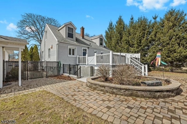 rear view of property with a playground, fence, and a chimney