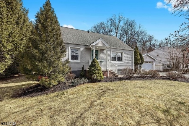 view of front of home featuring a garage, roof with shingles, a front lawn, and an outbuilding