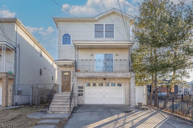 view of front of home featuring a garage, driveway, fence, and a balcony