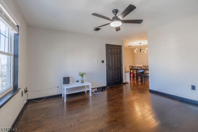 empty room with baseboards, visible vents, wood finished floors, and ceiling fan with notable chandelier