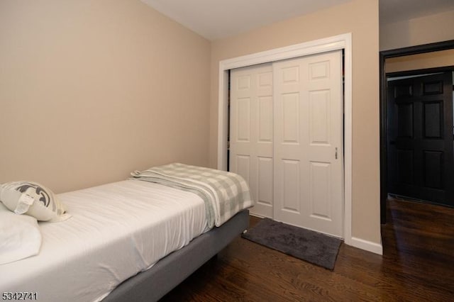 bedroom featuring dark wood-style floors, a closet, and baseboards