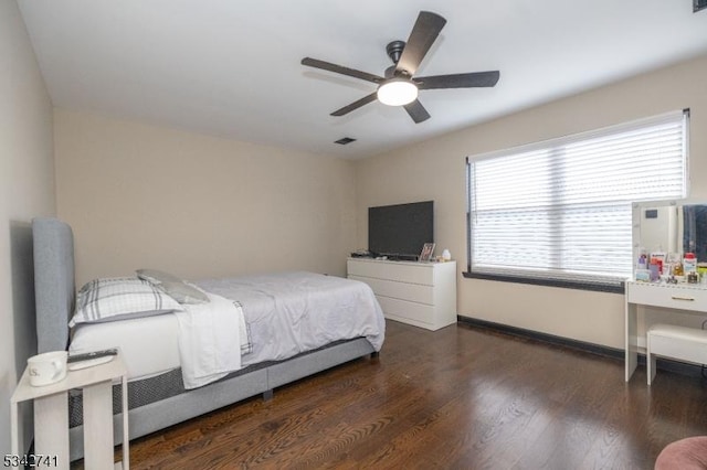 bedroom with a ceiling fan, wood finished floors, visible vents, and baseboards