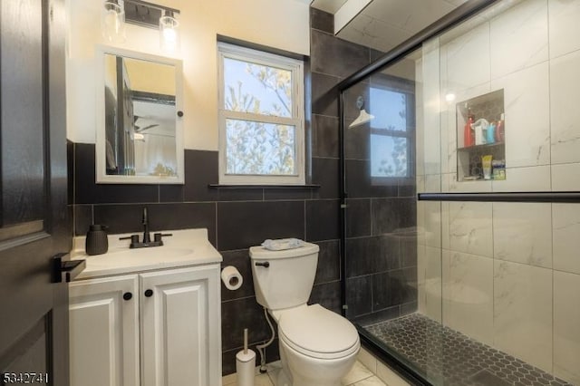 full bathroom with toilet, a stall shower, tile walls, and vanity