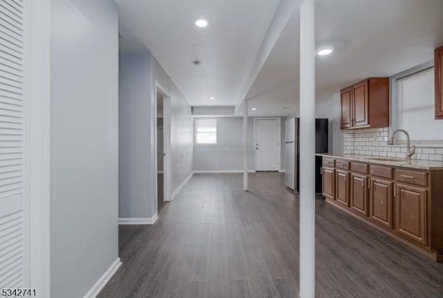 kitchen with tasteful backsplash, dark wood-type flooring, freestanding refrigerator, a sink, and baseboards