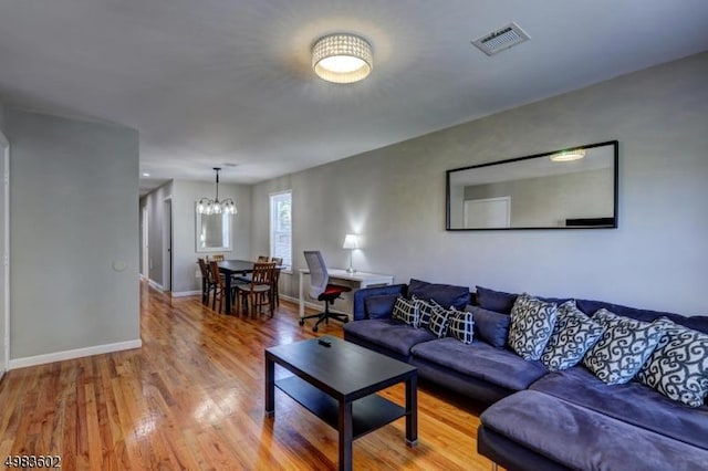 living room featuring visible vents, baseboards, wood finished floors, and a chandelier