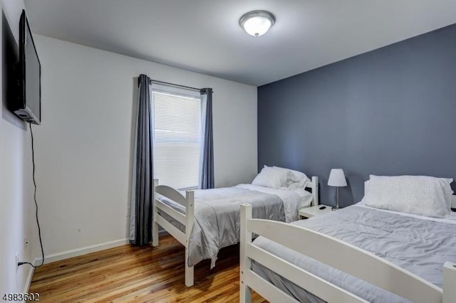 bedroom featuring light wood finished floors and baseboards