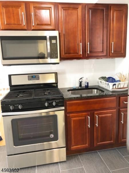 kitchen with decorative backsplash, dark stone countertops, appliances with stainless steel finishes, and a sink