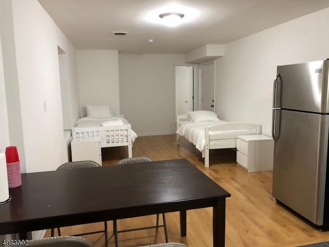 bedroom featuring visible vents, light wood-style flooring, and freestanding refrigerator