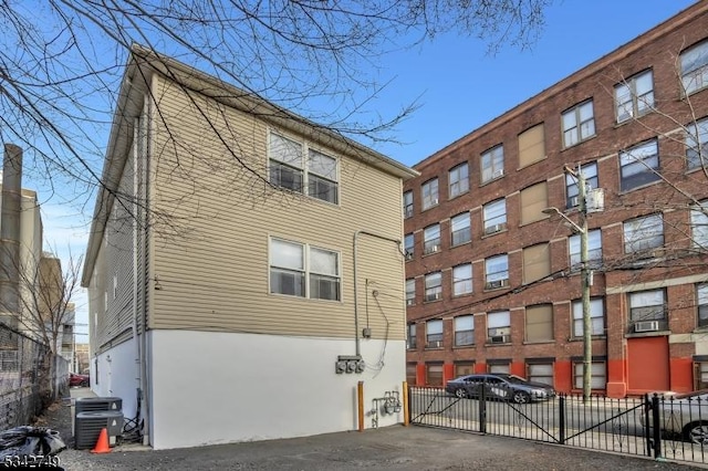 view of building exterior with cooling unit and fence