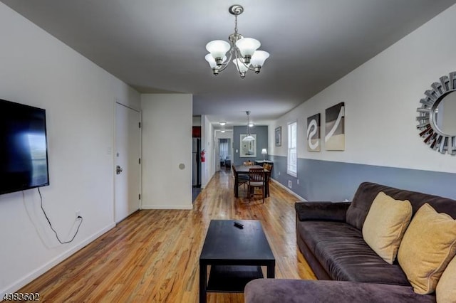 living room with an inviting chandelier, baseboards, and light wood-style floors