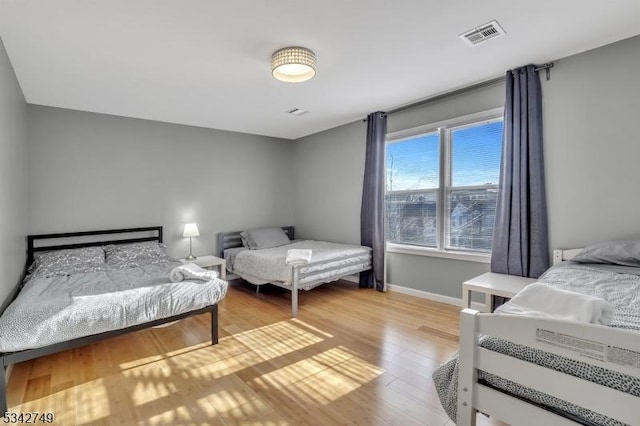 bedroom with visible vents, baseboards, and wood finished floors