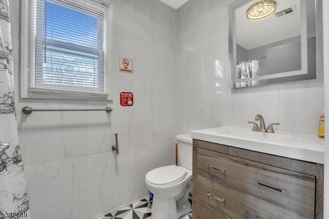 bathroom featuring visible vents, toilet, tile walls, and vanity