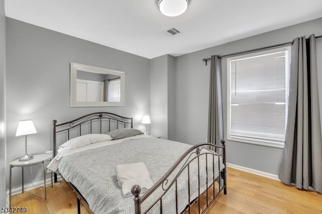 bedroom featuring visible vents, light wood-style flooring, and baseboards