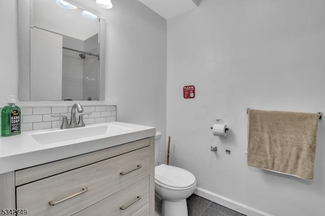 full bath featuring toilet, backsplash, a shower, baseboards, and vanity