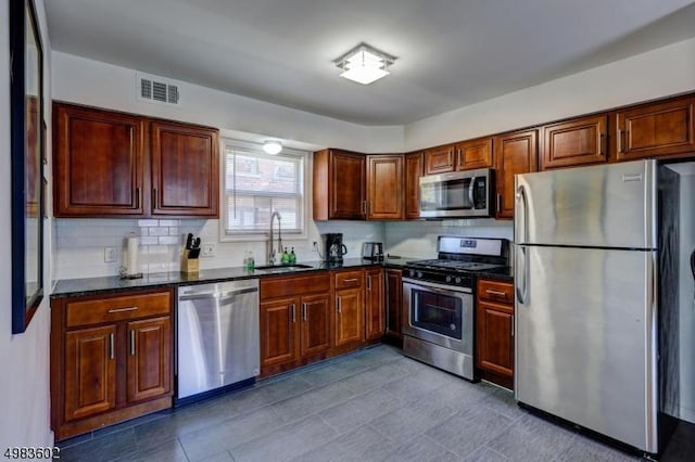 kitchen with backsplash, visible vents, appliances with stainless steel finishes, and a sink