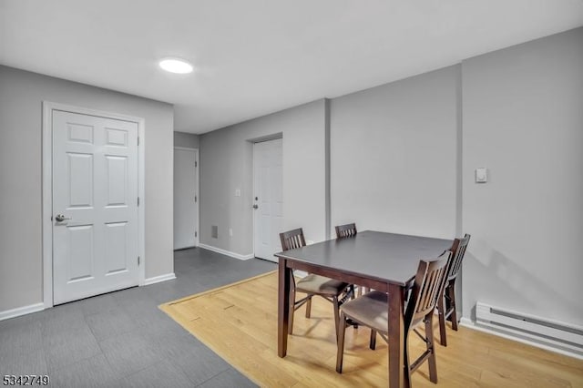 dining area with baseboards, baseboard heating, and wood finished floors