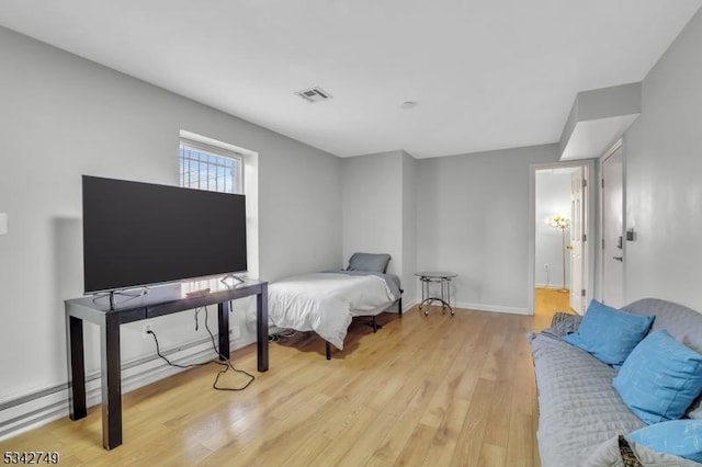 bedroom with light wood finished floors, visible vents, and baseboards