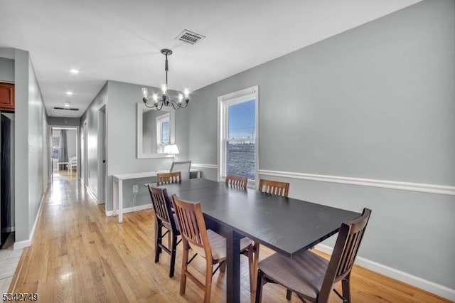 dining space with a chandelier, visible vents, baseboards, and light wood-style floors