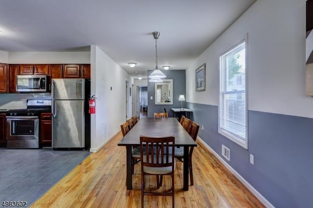 dining space with light wood-style flooring, baseboards, and visible vents