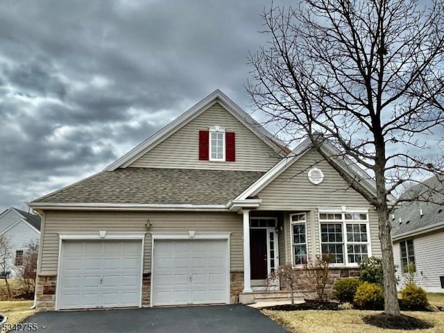 view of front of home featuring a garage, stone siding, driveway, and a shingled roof