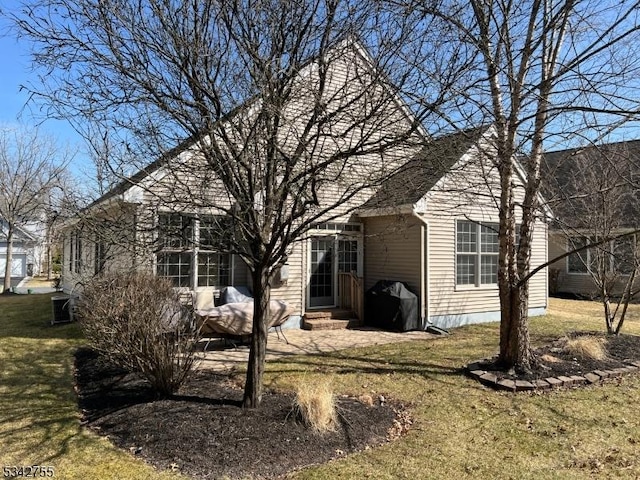 back of property with entry steps and a lawn