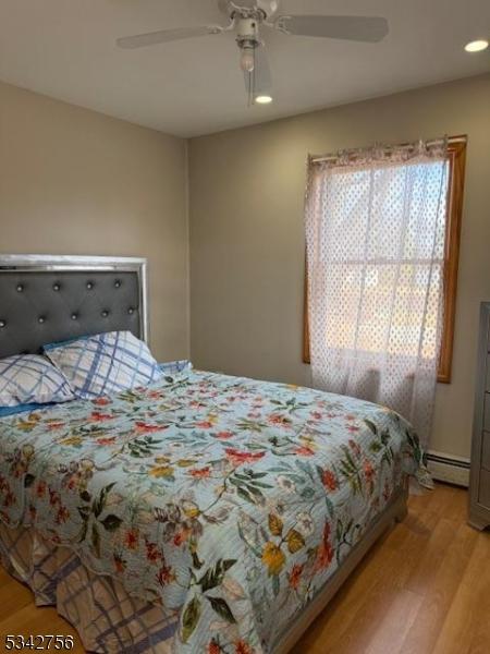 bedroom featuring recessed lighting, a baseboard radiator, light wood-style floors, and ceiling fan