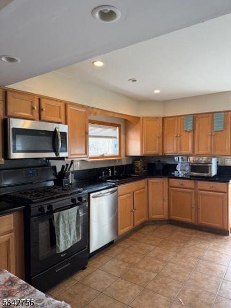 kitchen featuring dark countertops, recessed lighting, brown cabinetry, stainless steel appliances, and a sink