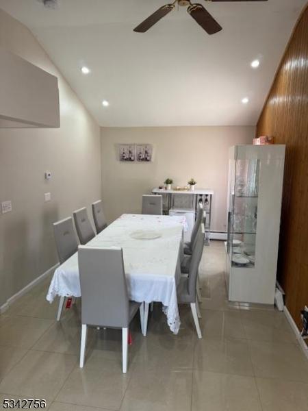 dining space with a ceiling fan, recessed lighting, light tile patterned floors, baseboard heating, and vaulted ceiling